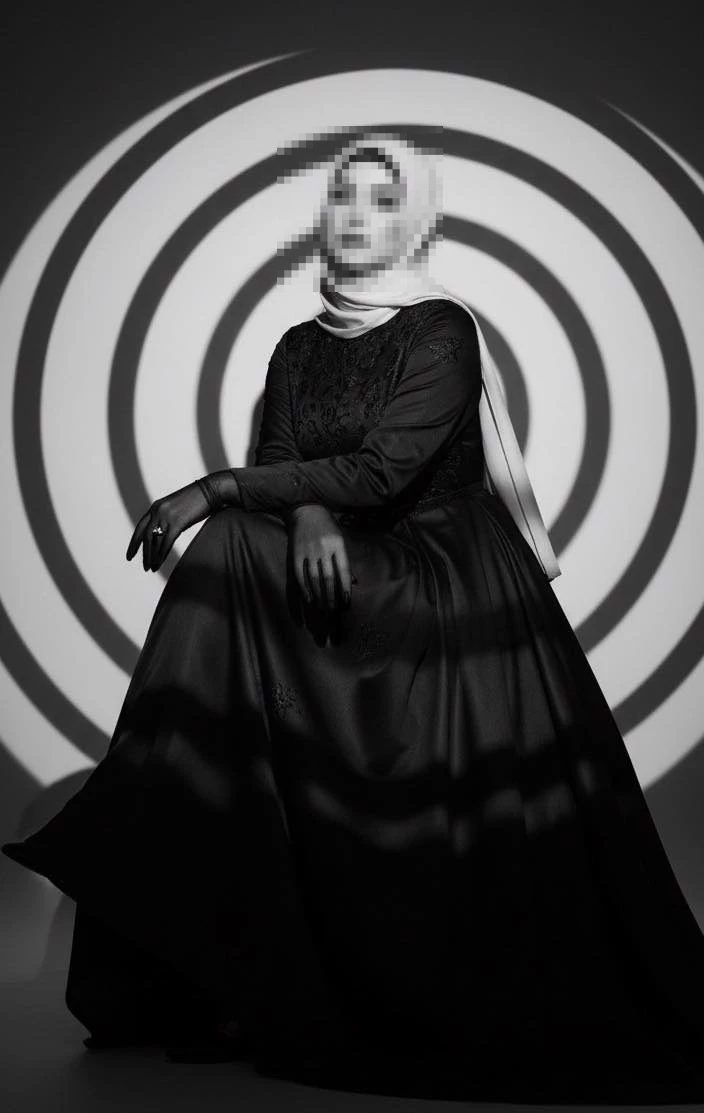 Elegant woman in black gown and light hijab under artistic circular lighting