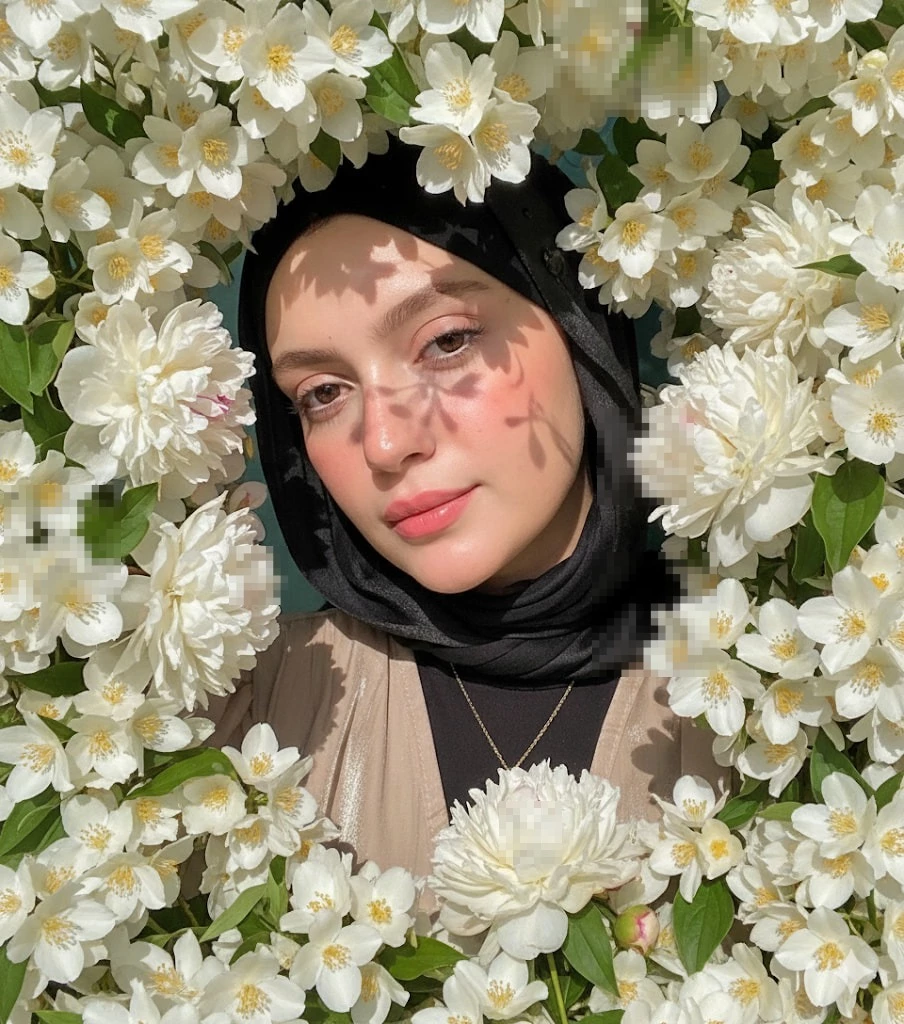 Elegant woman in white hijab with butteWoman in black hijab surrounded by blooming white flowers under soft sunlightrfly clips and pearl necklace in sunlight