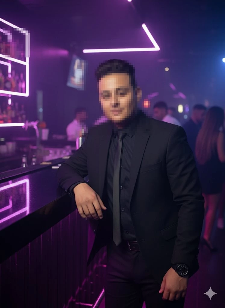 Man in black suit posing confidently at modern neon lit nightclub bar