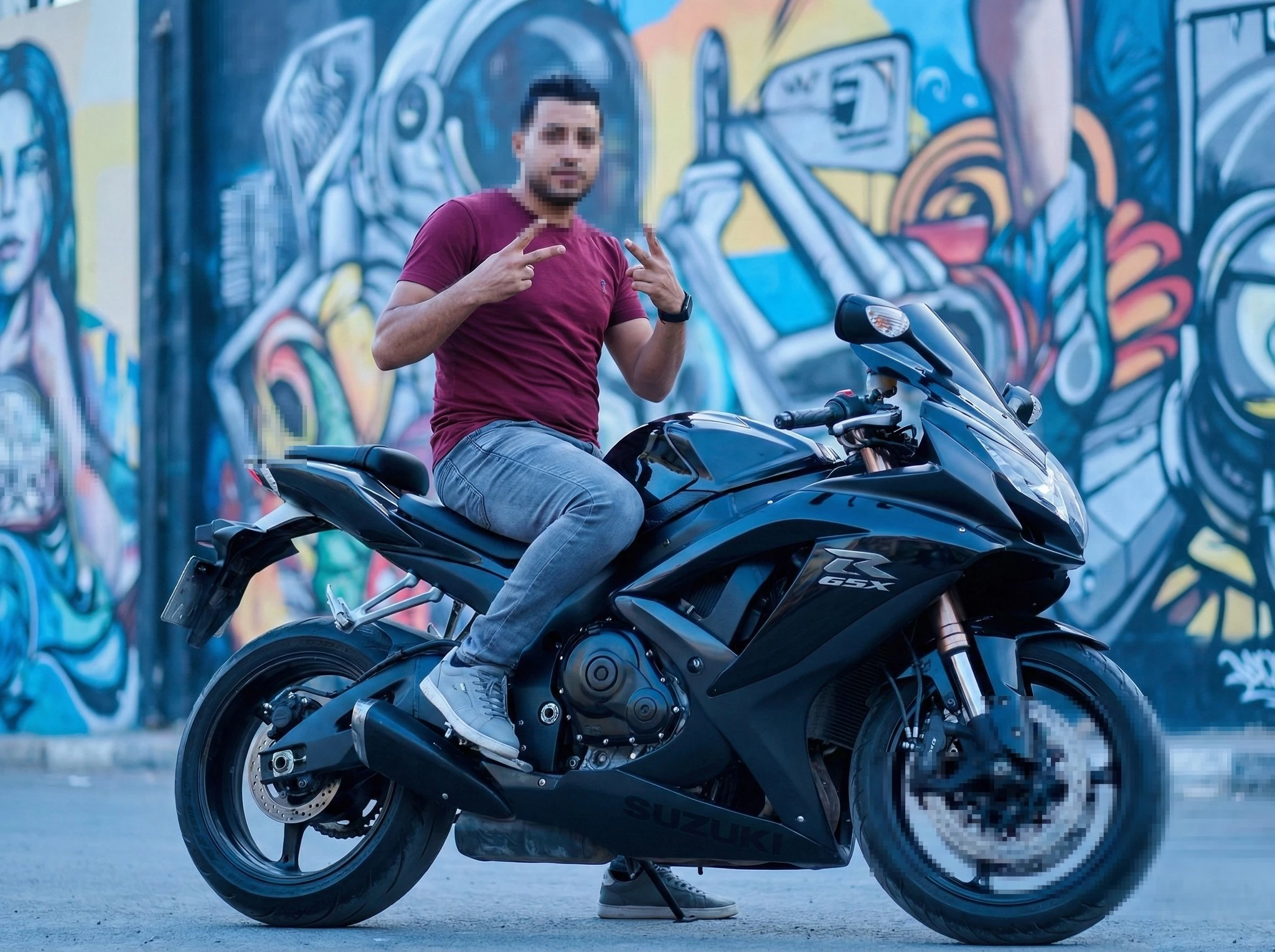 Man Posing on a Black Suzuki GSX Motorcycle in Front of Colorful Graffiti Art