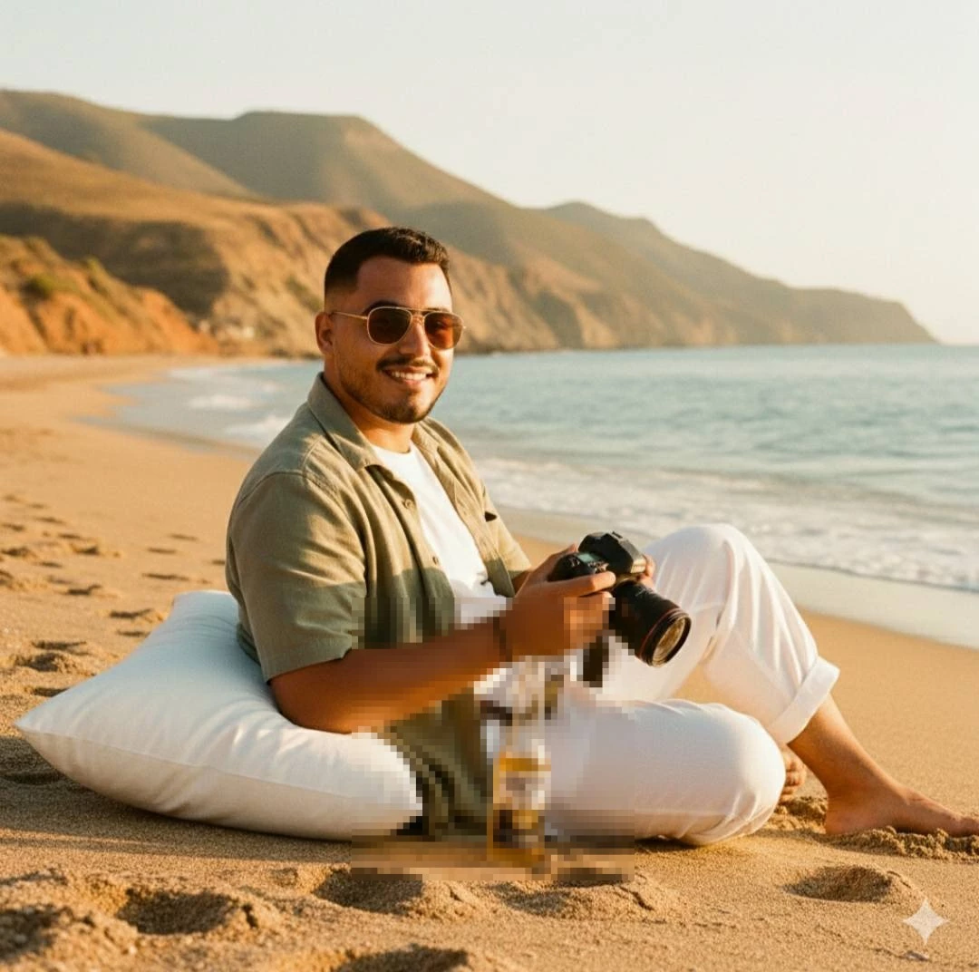 Man Sitting on the Beach at Sunset Holding a Camera and Enjoying the View