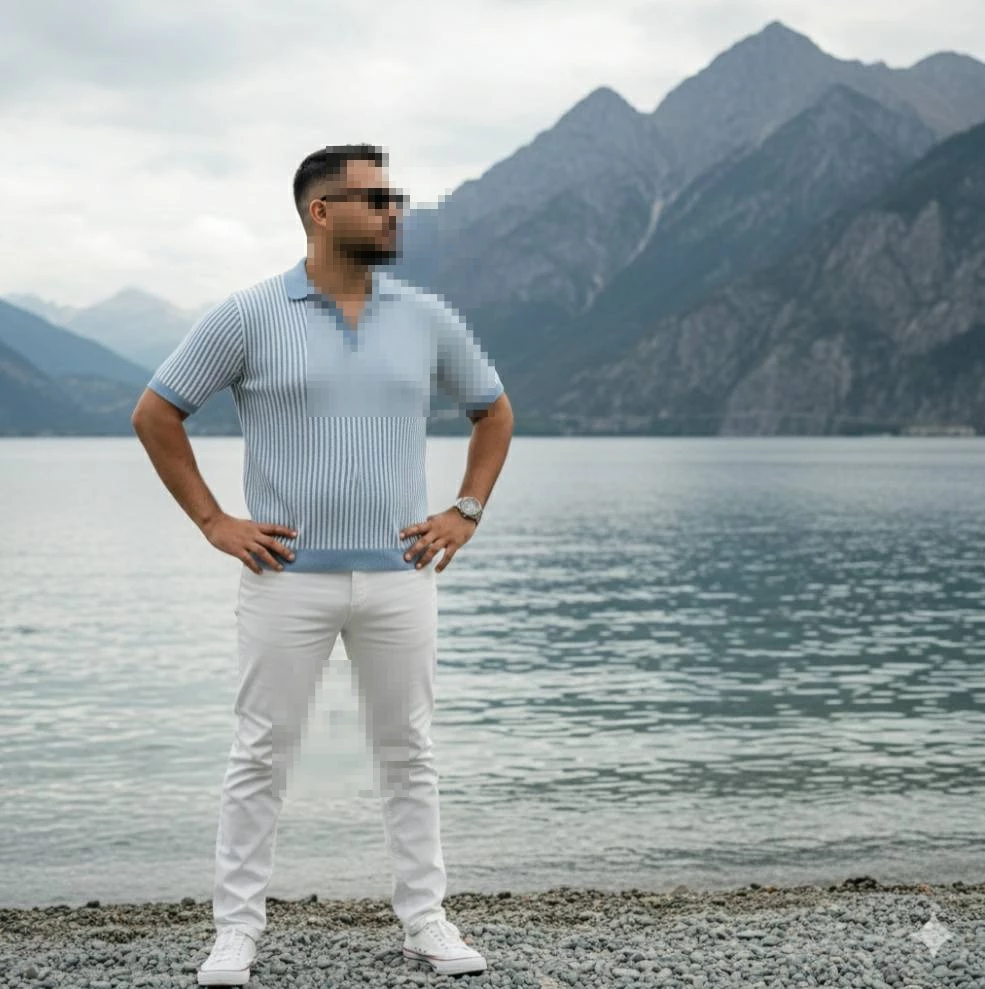 Man standing confidently by lake wearing light blue shirt and white pants