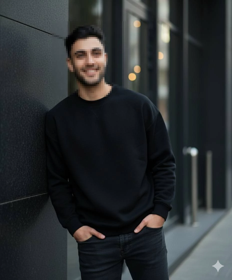 Smiling Man in Black Sweatshirt Leaning Against Modern City Wall