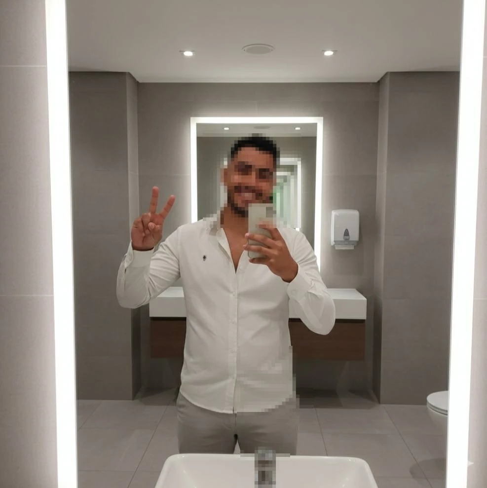 Smiling Man Taking Mirror Selfie in Modern Bathroom with Bright Lighting