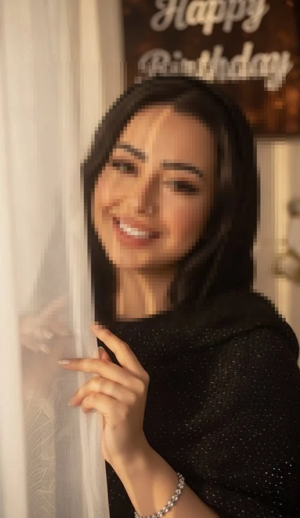 Smiling woman in black shawl standing by curtain in warm golden light