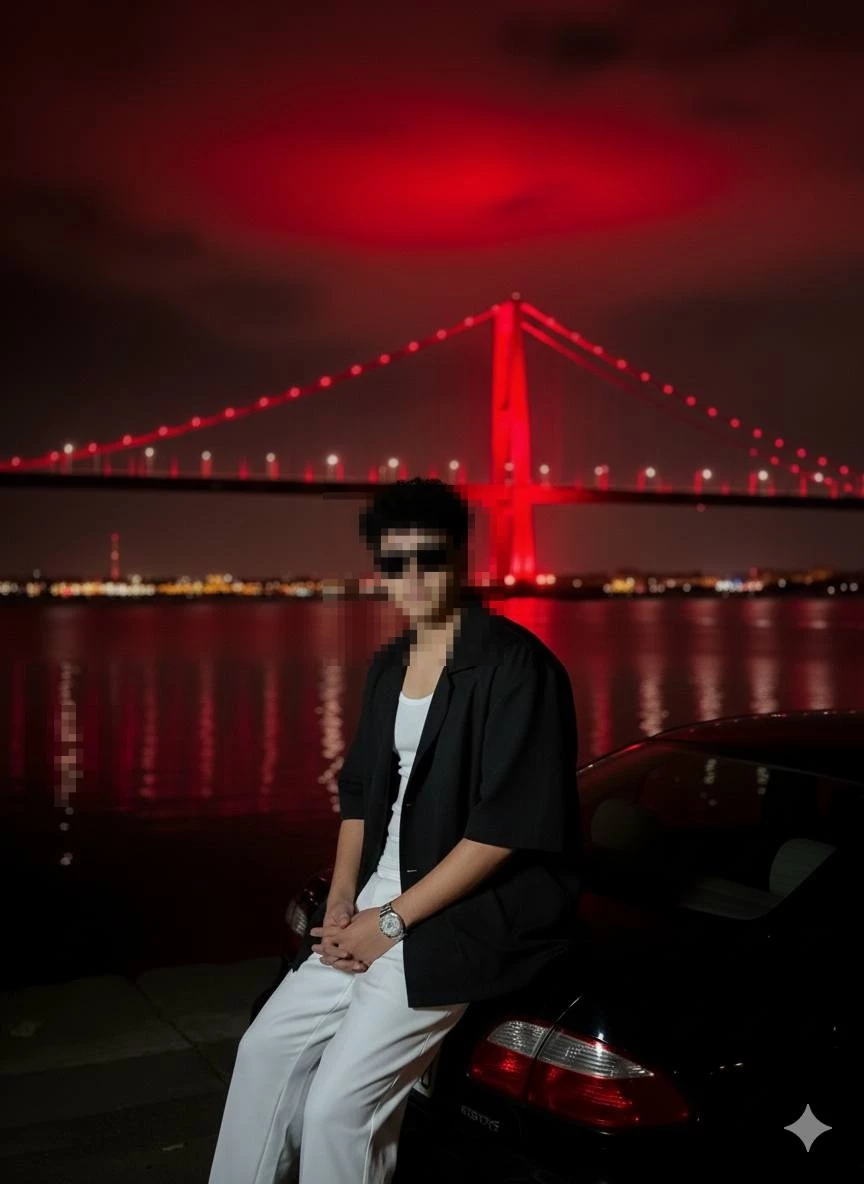 Stylish Man Sitting by Car at Night with Red Bridge Reflected on Water