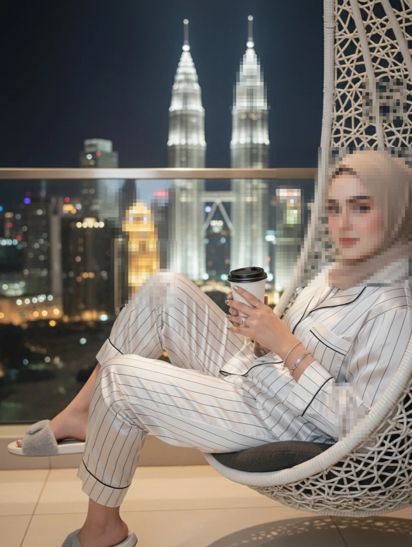 Woman in Hijab Relaxing on Balcony at Night with Petronas Towers View