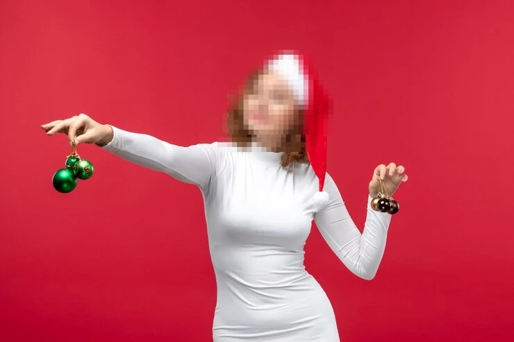 Woman in White Dress Holding Christmas Ornaments Against a Festive Red Background