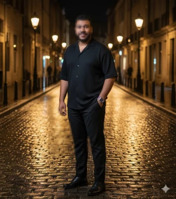 Confident man standing on a cobblestone street at night under warm streetlights
