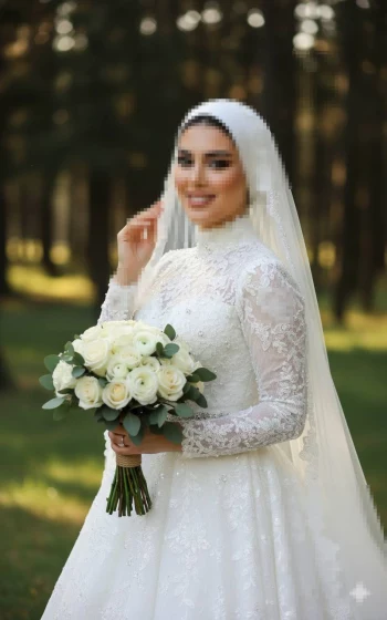 Elegant bride in white lace gown holding rose bouquet in sunlit forest