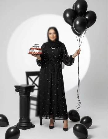Elegant woman in black dress holding birthday cake and black balloons