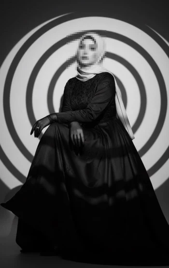 Elegant woman in black gown and light hijab under artistic circular lighting