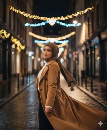 Elegant woman in brown coat walking under festive street lights at night