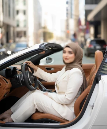 Elegant woman in brown hijab driving luxury white convertible in the city