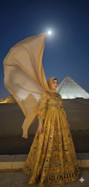 Elegant woman in golden Egyptian dress standing by pyramid under moonlit sky