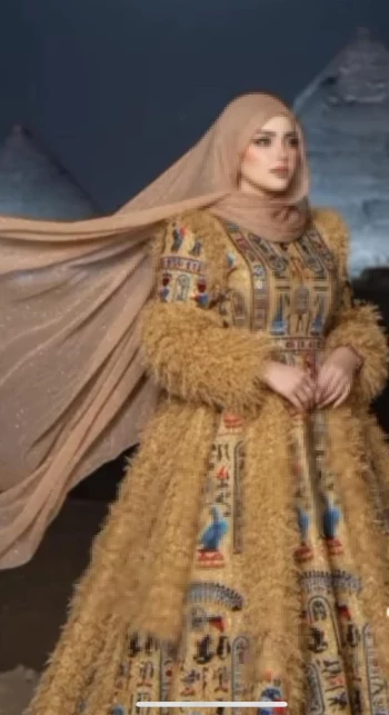 Elegant woman in golden pharaonic dress posing near the Great Pyramids at night