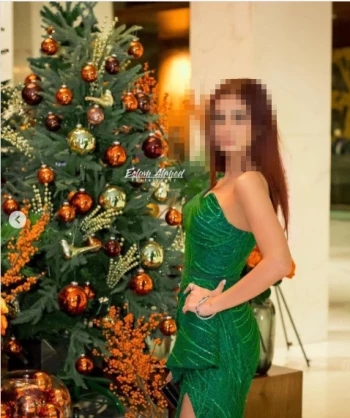 Elegant Woman in Green Dress Posing Beside a Festive Christmas Tree
