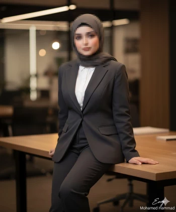 Elegant woman in grey business suit and hijab posing confidently in modern office