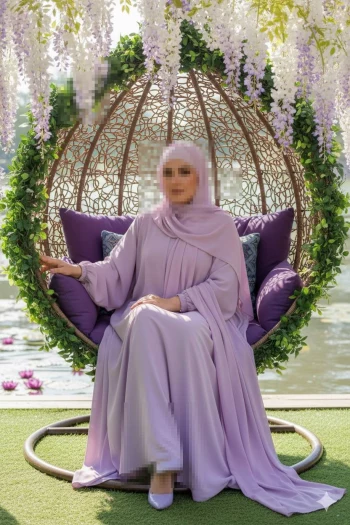 Elegant woman in lilac abaya sitting on floral hanging chair by the lake