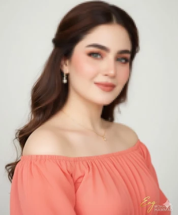 Elegant woman in peach off shoulder blouse with soft curls and pearl earrings