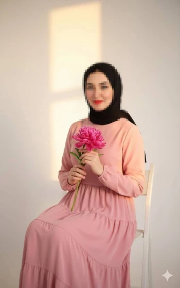 Elegant woman in pink dress holding a flower with natural sunlight background