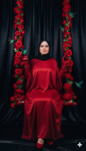 Elegant woman in red satin dress sitting on rose swing with black background