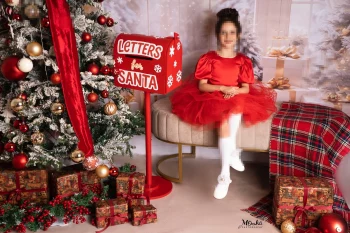 Festive Christmas Portrait of a Child Sitting Beside a Holiday Tree and Santa Mailbox
