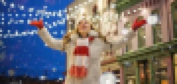 Joyful Woman Celebrating Winter Snow Under Festive Holiday Lights