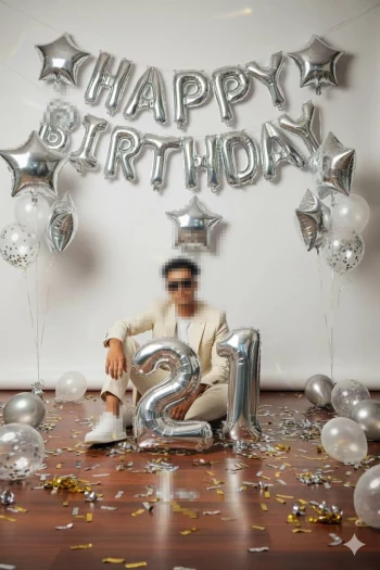 Man celebrating 21st birthday with silver balloons and confetti decorations