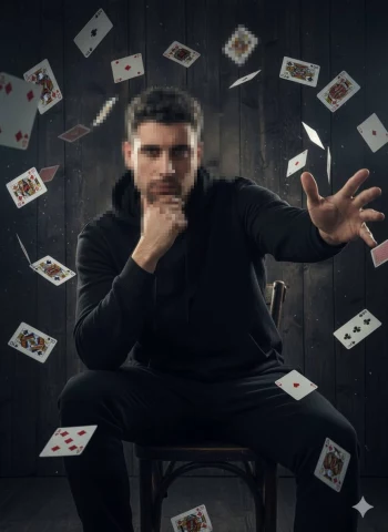 Man in Black Hoodie Controlling Floating Playing Cards in Dramatic Lighting