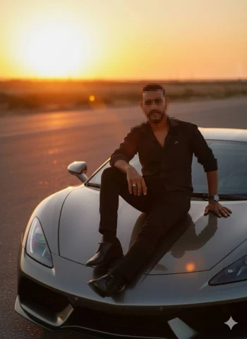 Man in black outfit sitting on silver sports car during golden sunset
