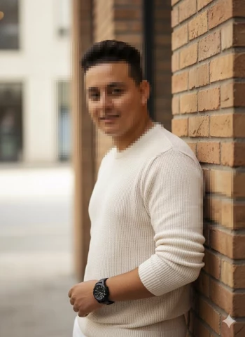 Man in cream sweater posing confidently by brick wall in urban setting