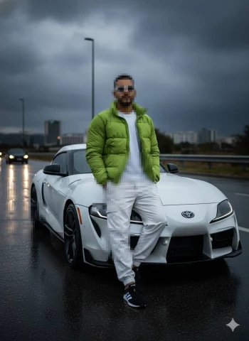 Man in green jacket posing with white Toyota Supra on rainy city road