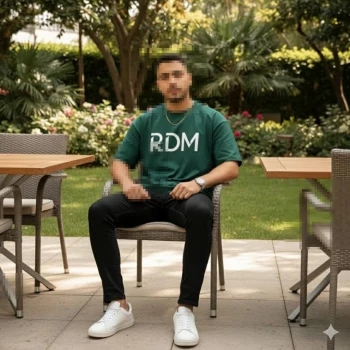 Man in green RDM shirt sitting confidently in outdoor garden café setting