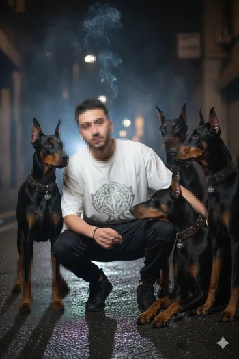 Man in white shirt posing at night with four Doberman dogs on city street