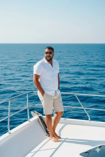 Man in White Shirt Relaxing on Yacht Deck with Blue Ocean View