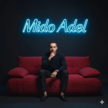Man sitting on red sofa under neon sign reading Mido Adel in dark studio