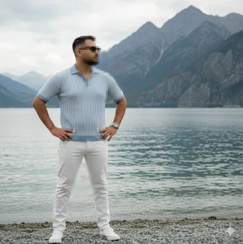 Man standing confidently by lake wearing light blue shirt and white pants