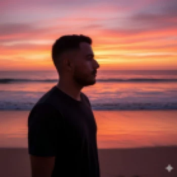 Man Standing on Beach at Sunset with Vibrant Orange and Pink Sky