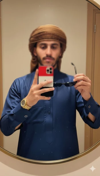 Man Taking Mirror Selfie in Blue Thobe and Brown Headscarf Indoors