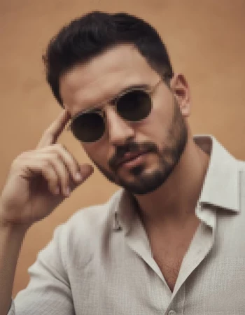 Man wearing light cream shirt and round sunglasses posing confidently outdoors