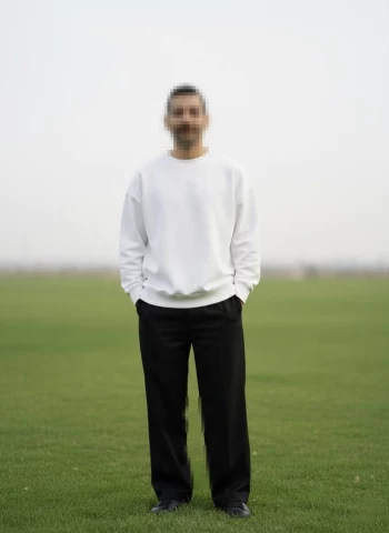 Minimalist outdoor portrait of a man standing on a grassy field
