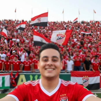 Smiling football fan in red jersey celebrating with crowd waving team flags