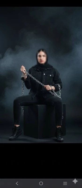Strong woman in black outfit holding metal chains in a dramatic smoky studio