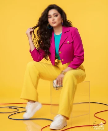 Stylish woman in vibrant pink blazer and yellow pants posing on yellow background