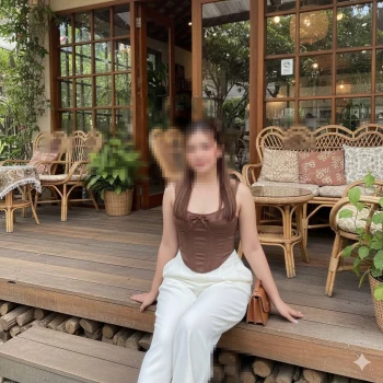 Stylish woman sitting on a wooden porch at a cozy café with rattan furniture