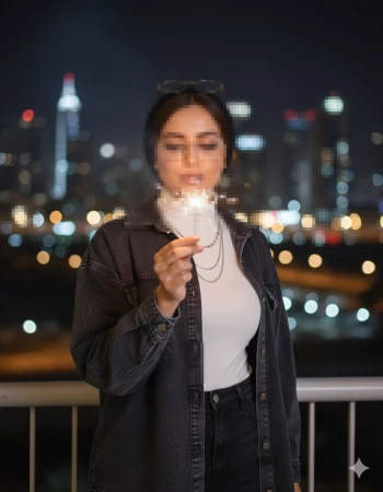 Woman holding sparkler on balcony at night with city lights in the background