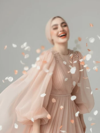 Woman in a flowing peach dress surrounded by falling petals in a soft studio scene