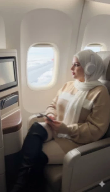 Woman in Hijab Relaxing by Airplane Window During Flight