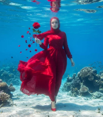Woman in Red Dress Holding Rose Underwater Among Coral Reef
